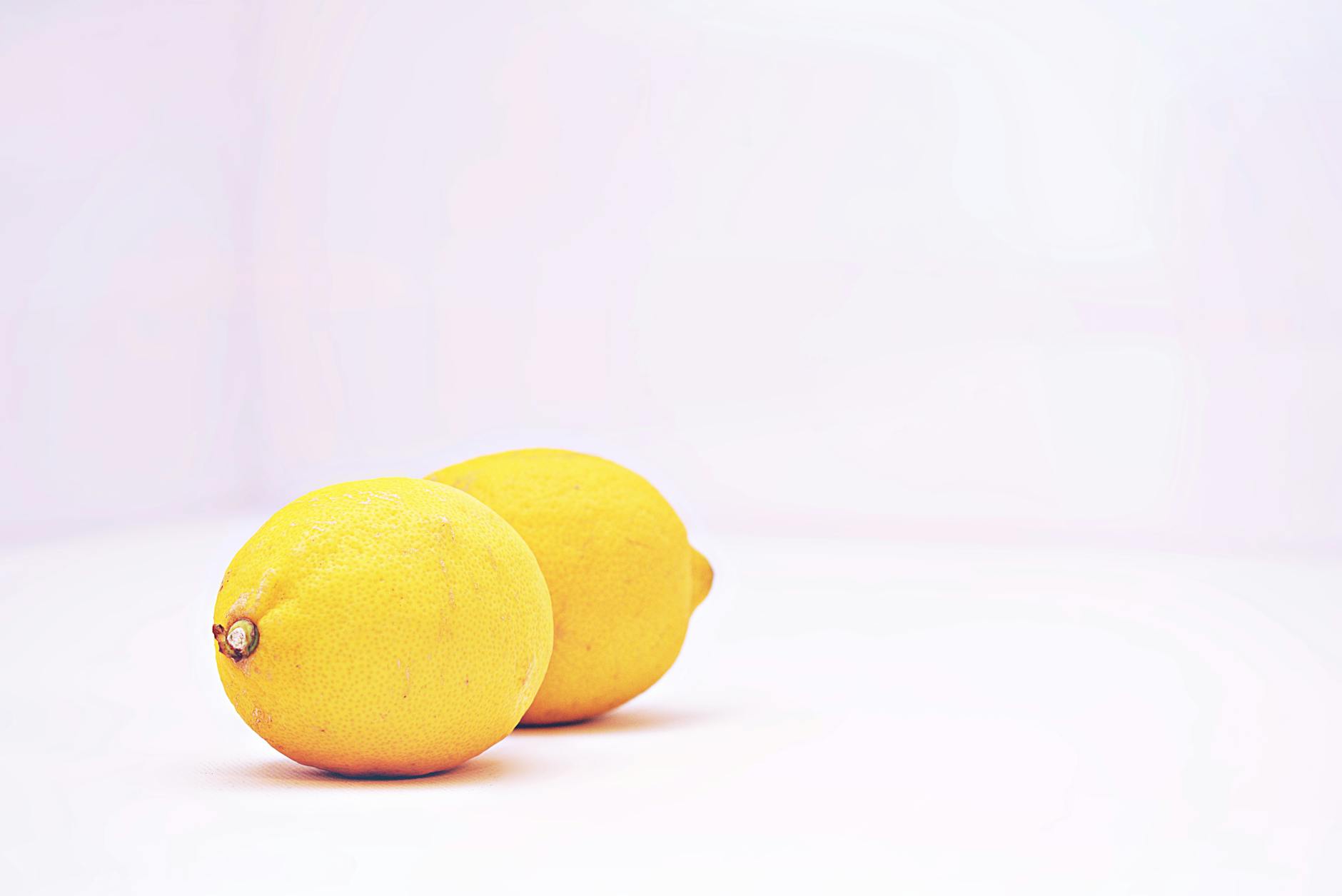 Two bright lemons on a white background, symbolizing fresh sensory experience and renewal