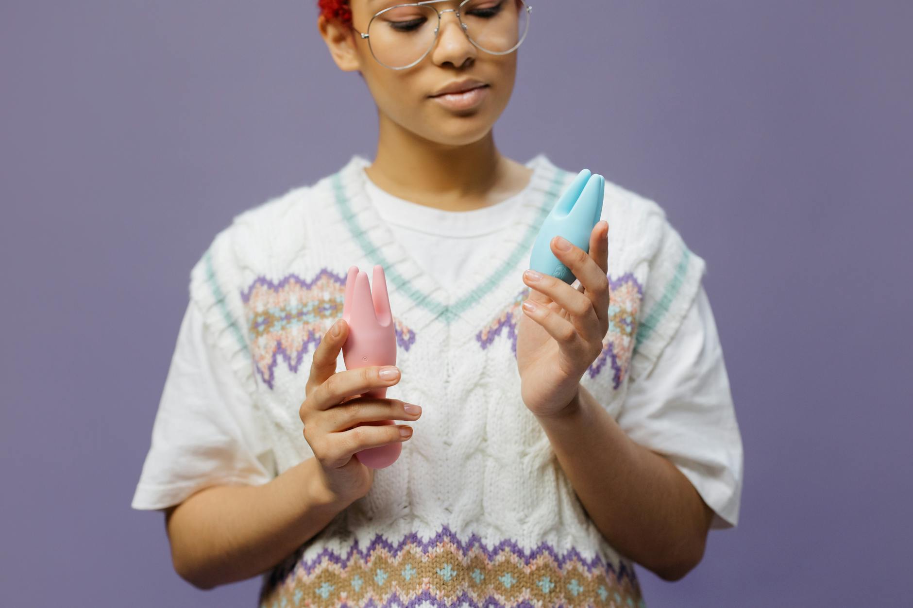 Woman holding a blue and pink silicone vibrator against her skin, exploring pleasure intentionally.
